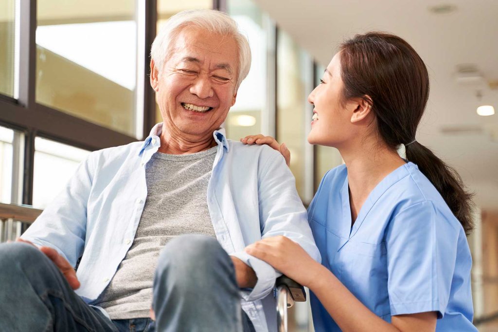 Patient in chair laughing with nurse squatting on ground