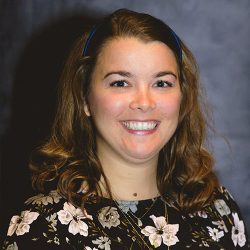 Lauren Cooley smiling at the camera, grey background.