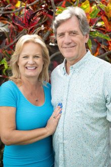 Sharon and Dr Scott smiling for camera in front of fall leaf