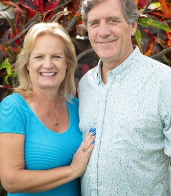 Sharon and Dr Scott smiling for camera in front of fall leaf